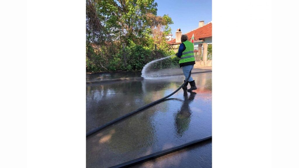 Служител мие улица с вода