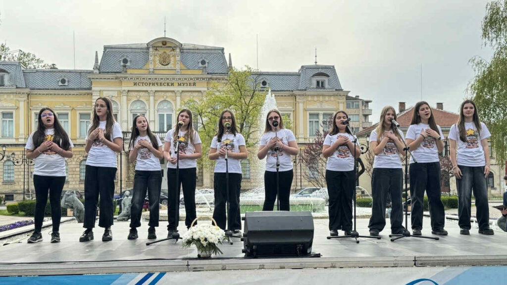 Деца пеят на сцена по случай честването на създаването на всеучилищния химн.